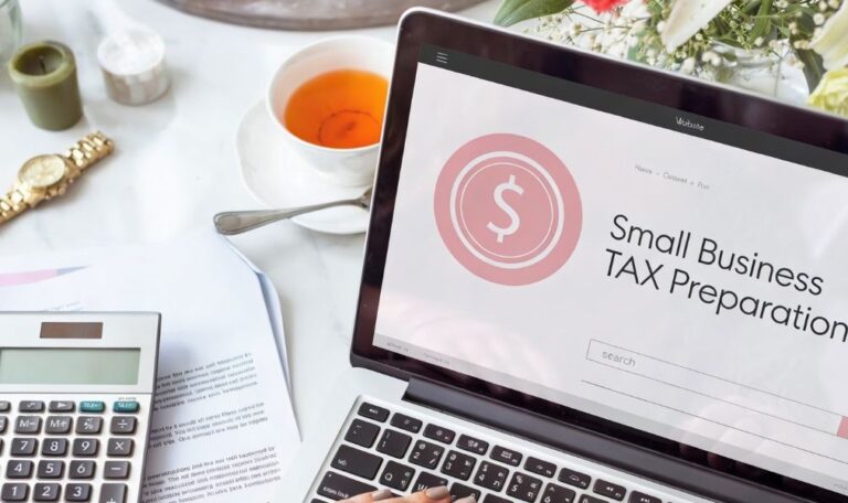 A laptop showing "Small Business Tax Preparation" next to a calculator and a cup of tea.